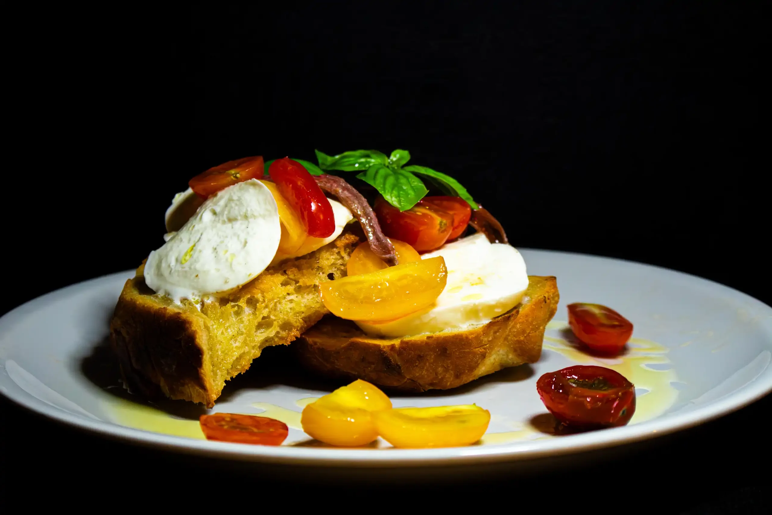 IMG_0315 Crostone di pane con burrata alici pomodorini e basilico su piatto bianco